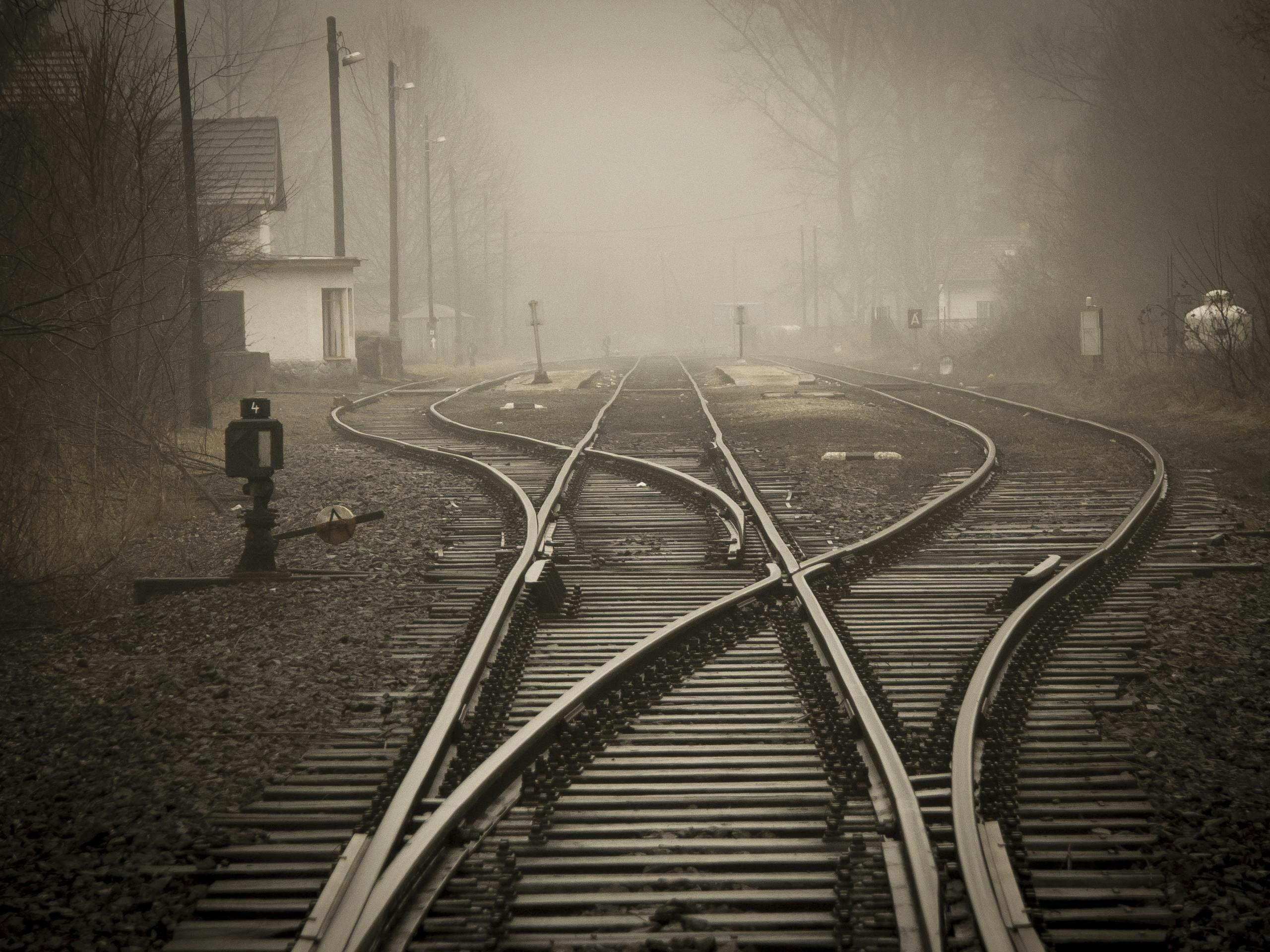 A person standing on the tracks in front of some buildings