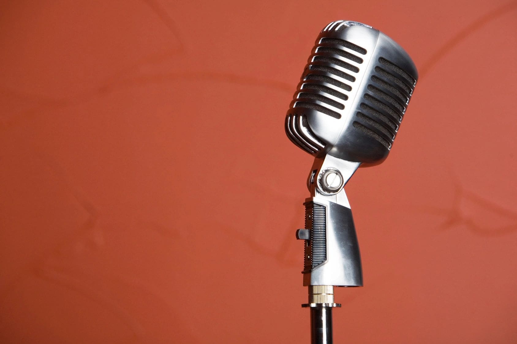 A microphone is on the stand against a red wall.